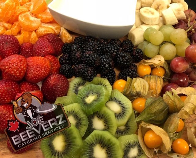 Assorted fresh fruits arranged on a platter with a central bowl for dipping