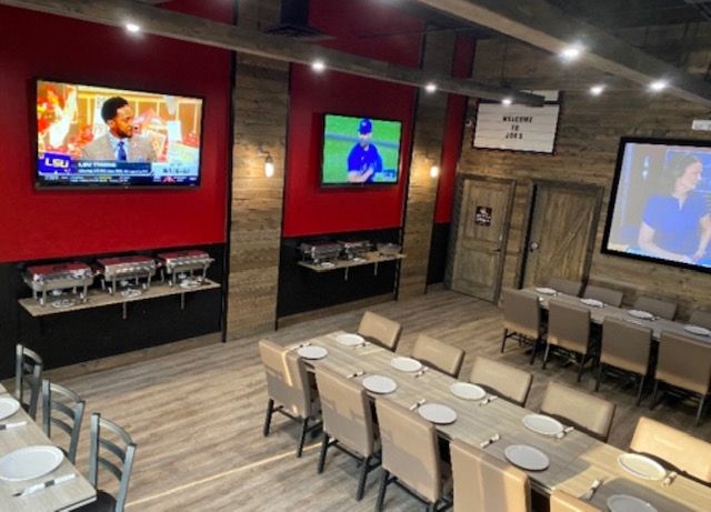 Sports bar with multiple TVs, empty tables, and red accent walls in a dining area