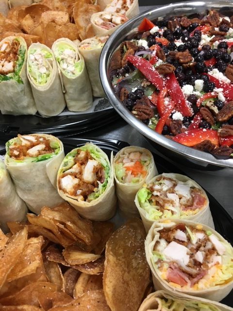 Wraps and fries beside a bowl of salad topped with berries and seeds