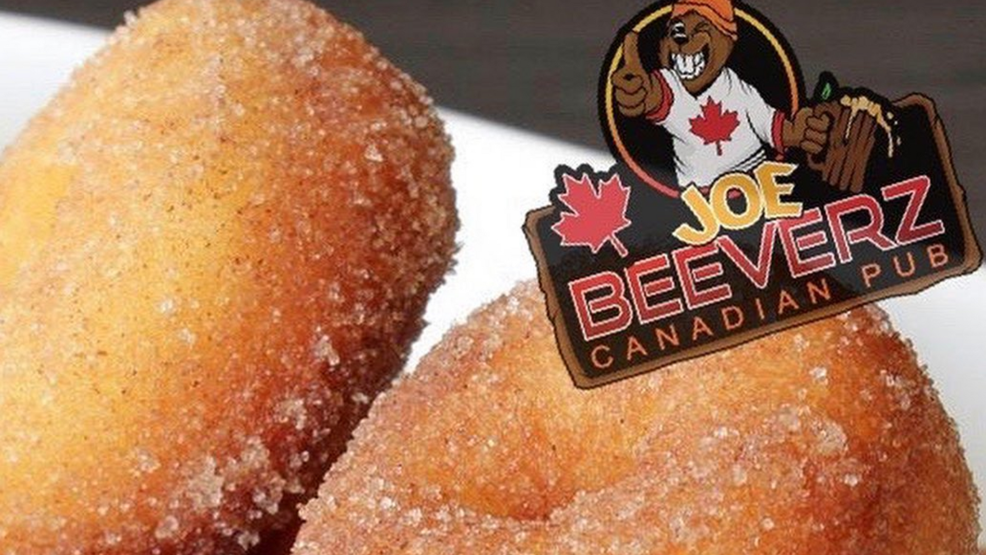 Close-up of sugared fried dough sticks with a Joe Beeverz Canadian Pub logo in the corner