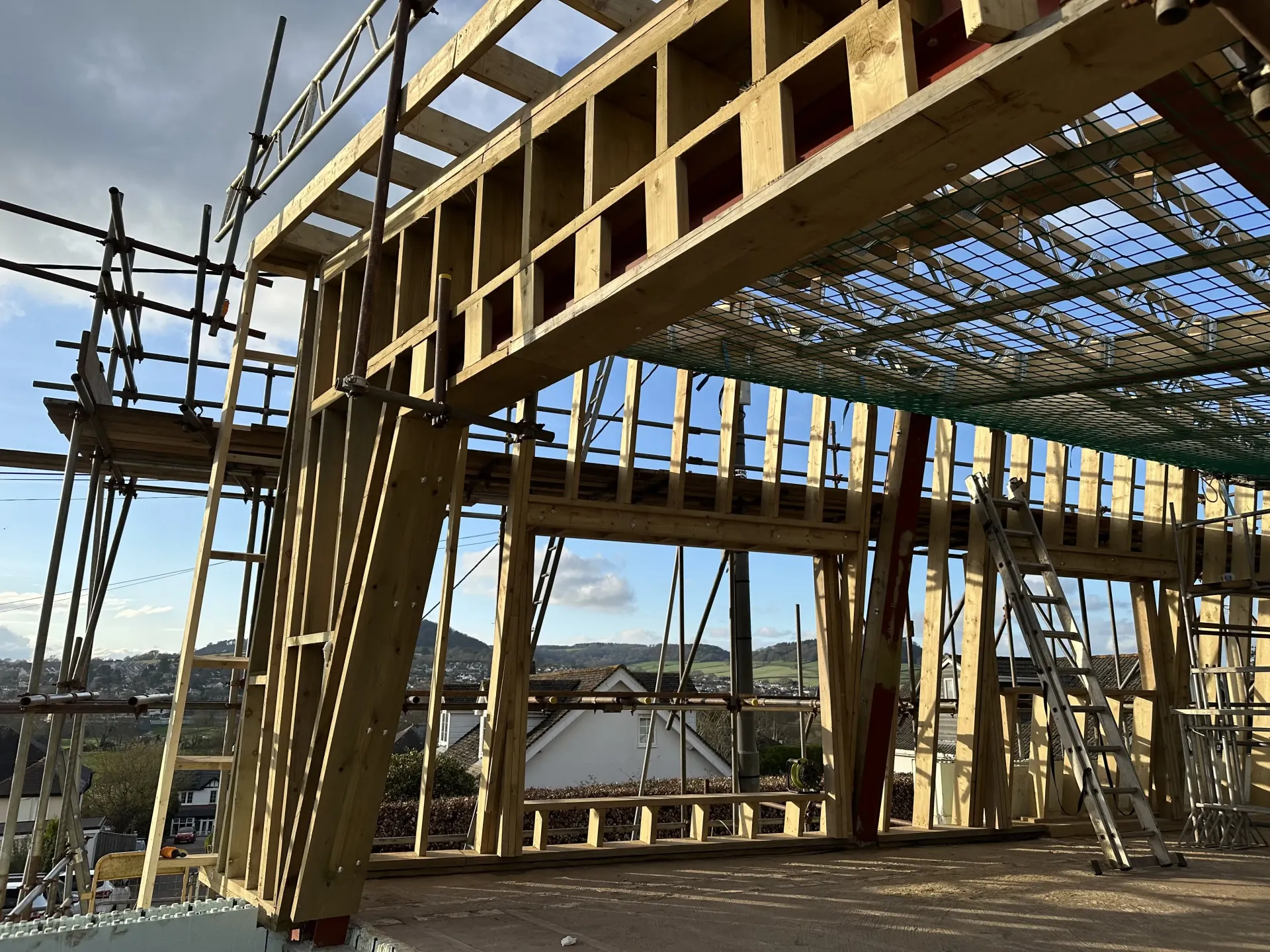 Wood-framed building under construction with scaffolding and workers on a bright day