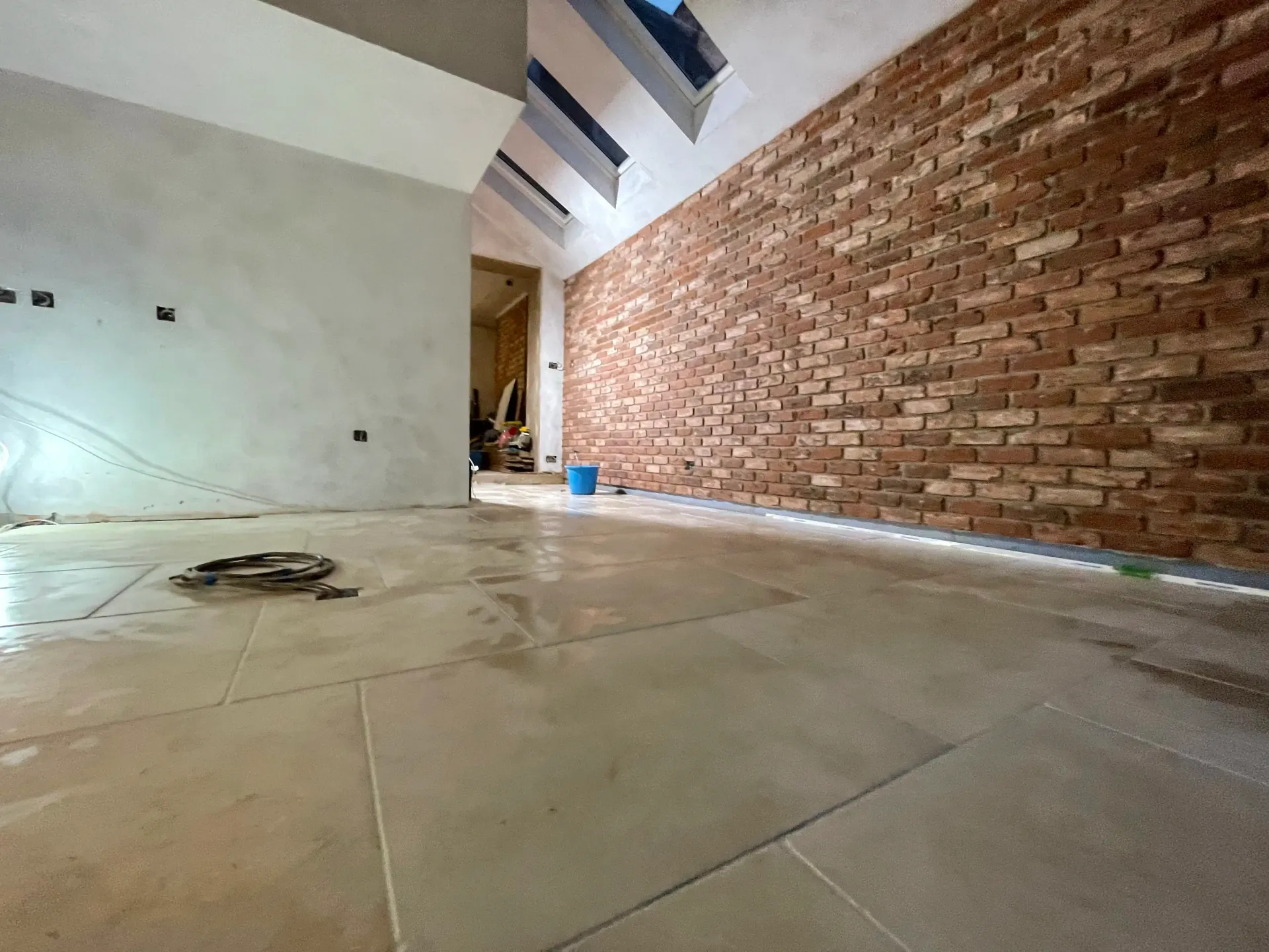 Empty room with tiled floor and exposed brick wall under construction