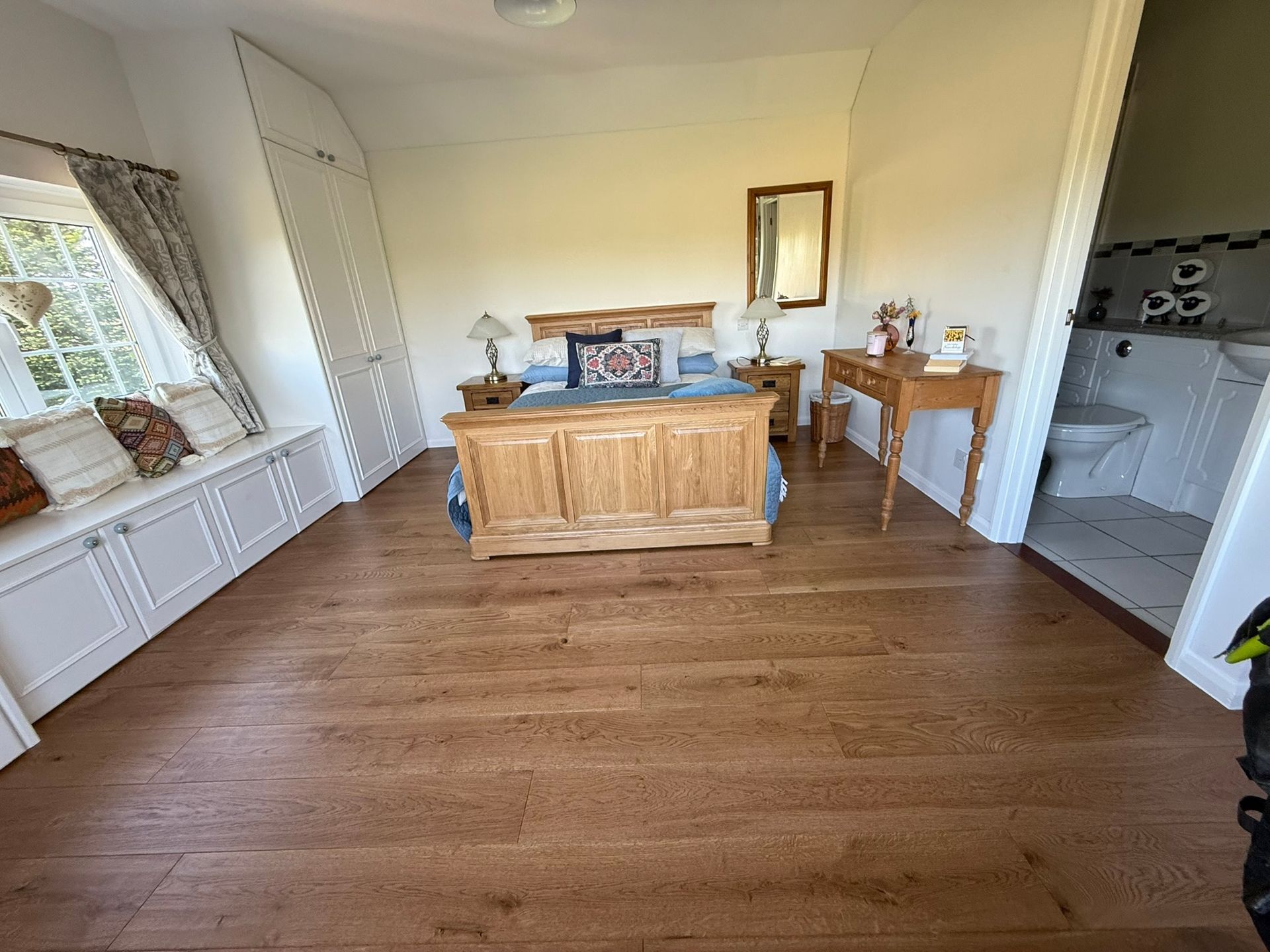 Bright living room with hardwood floors, white walls, large windows, and a wooden coffee table and side table.
