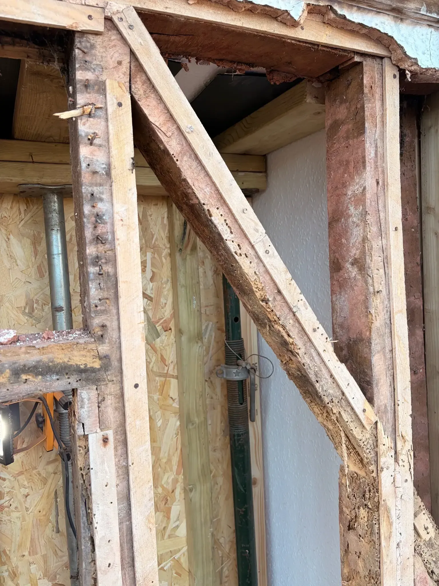 Wooden braces framing a damaged doorway in a partially stripped interior wall