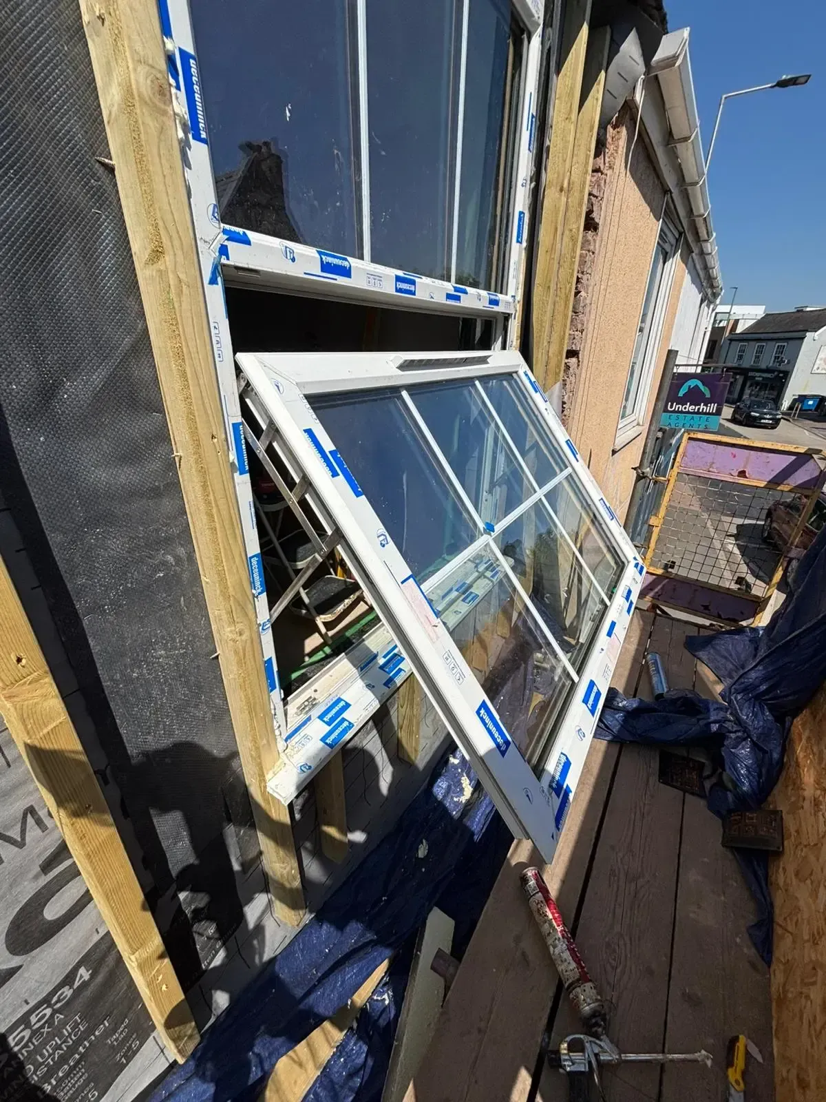 Tilted open window panes with shattered glass on a building exterior after damage or repair work