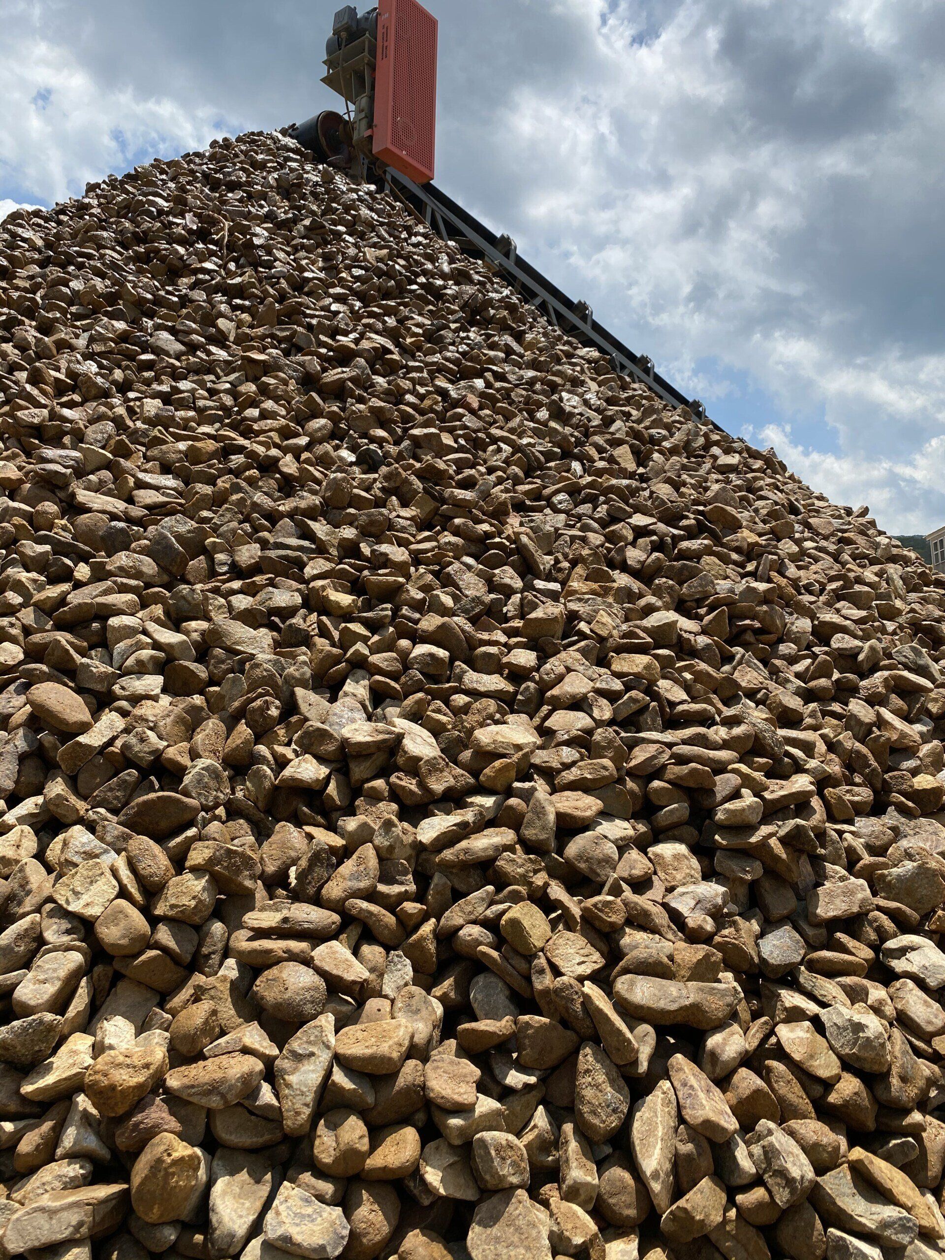 Large pile of tan rocks piled into a steep mound under a blue sky