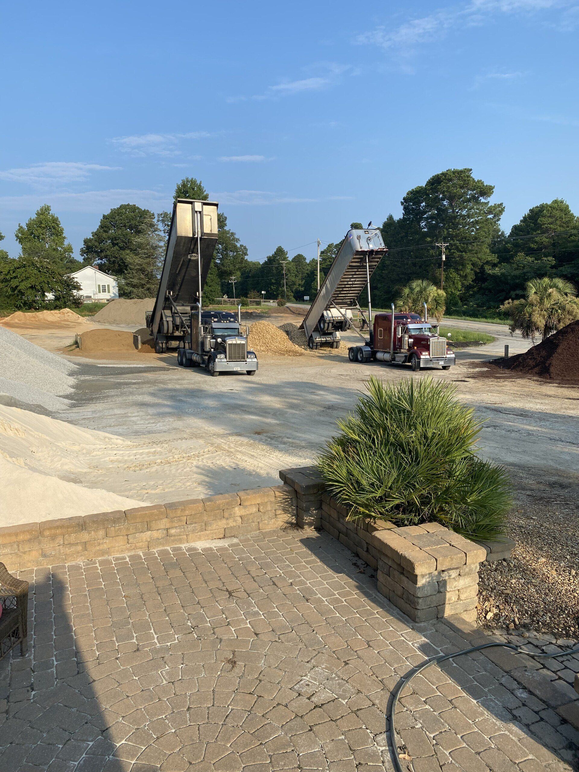 Construction site with two excavators and a dump truck on a gravel roadway under a blue sky