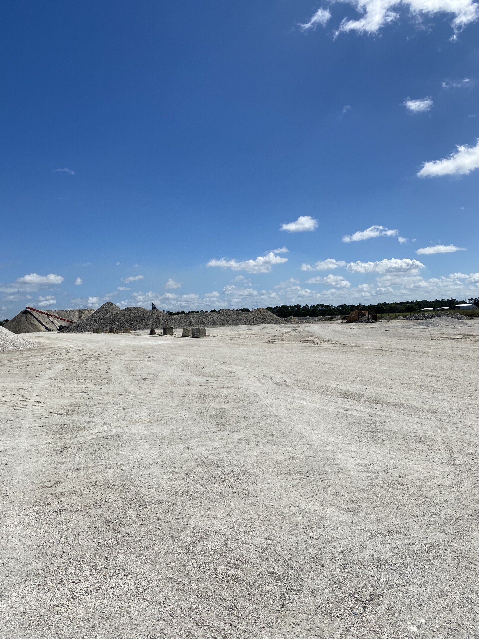 Landscape supply yard with piles of crushed stone under a blue sky