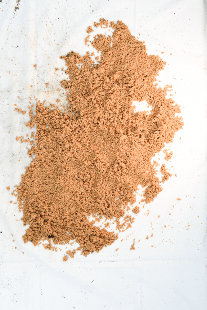 Pile of light brown granular material scattered on a white surface