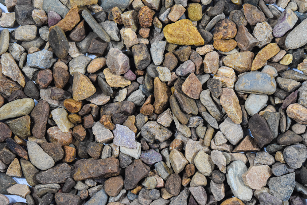 Close-up of mixed river rock landscaping stones in brown, gray, and gold tones.