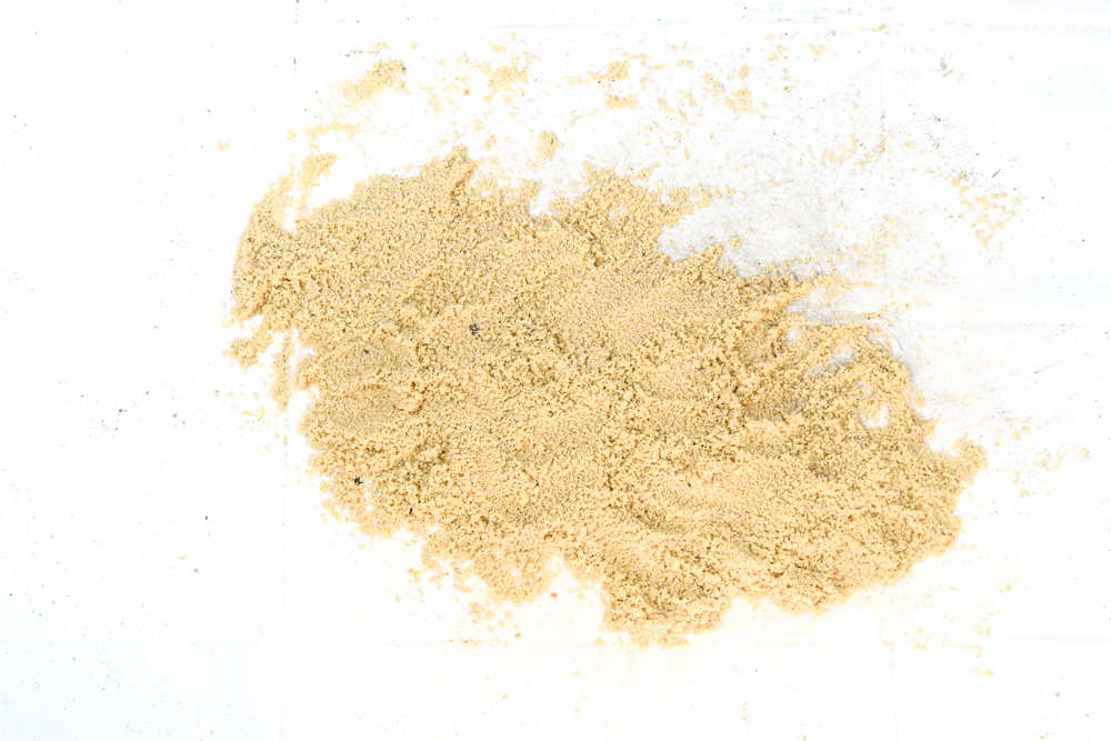 A mound of pale yellow powder on a white background.
