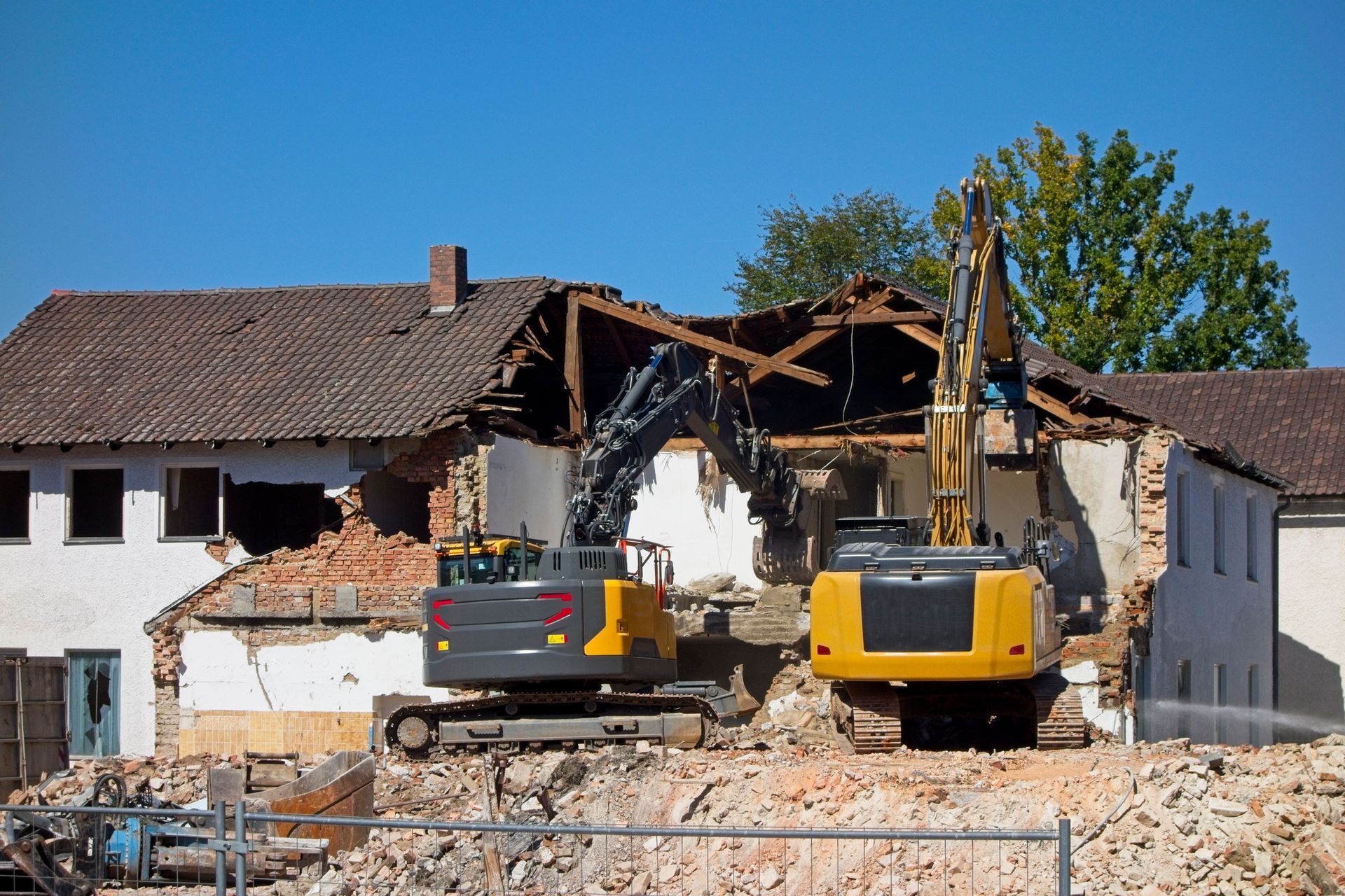 A yellow and black excavator is demolishing a building. A yellow and black excavator is demolishing a building.