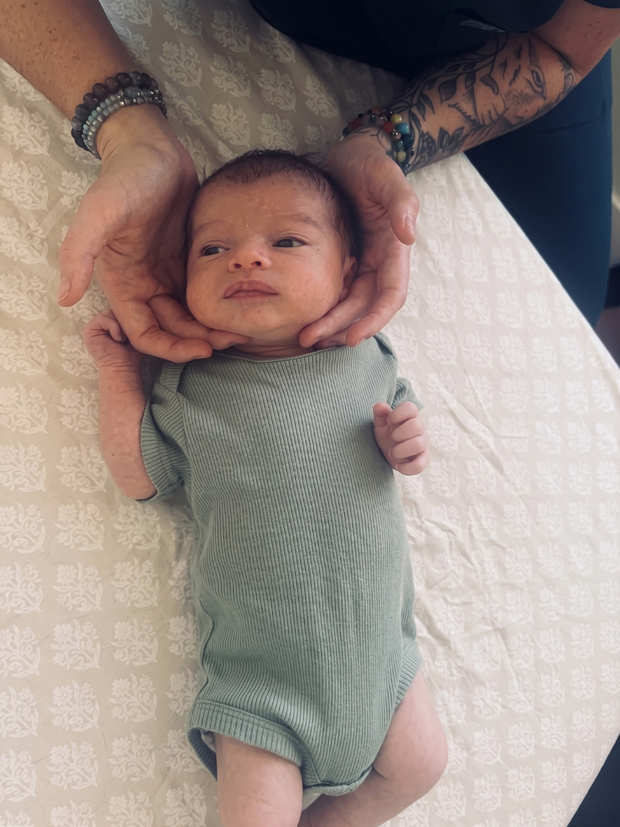 Woman gently massaging a baby on a changing table in a clinic room