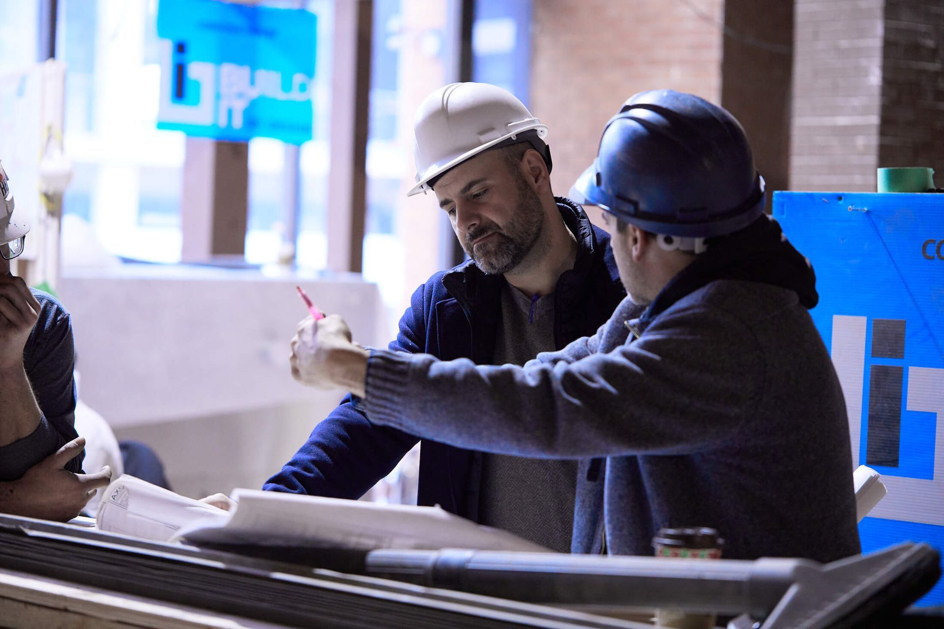 Two men wearing hard hats are looking at a blueprint.