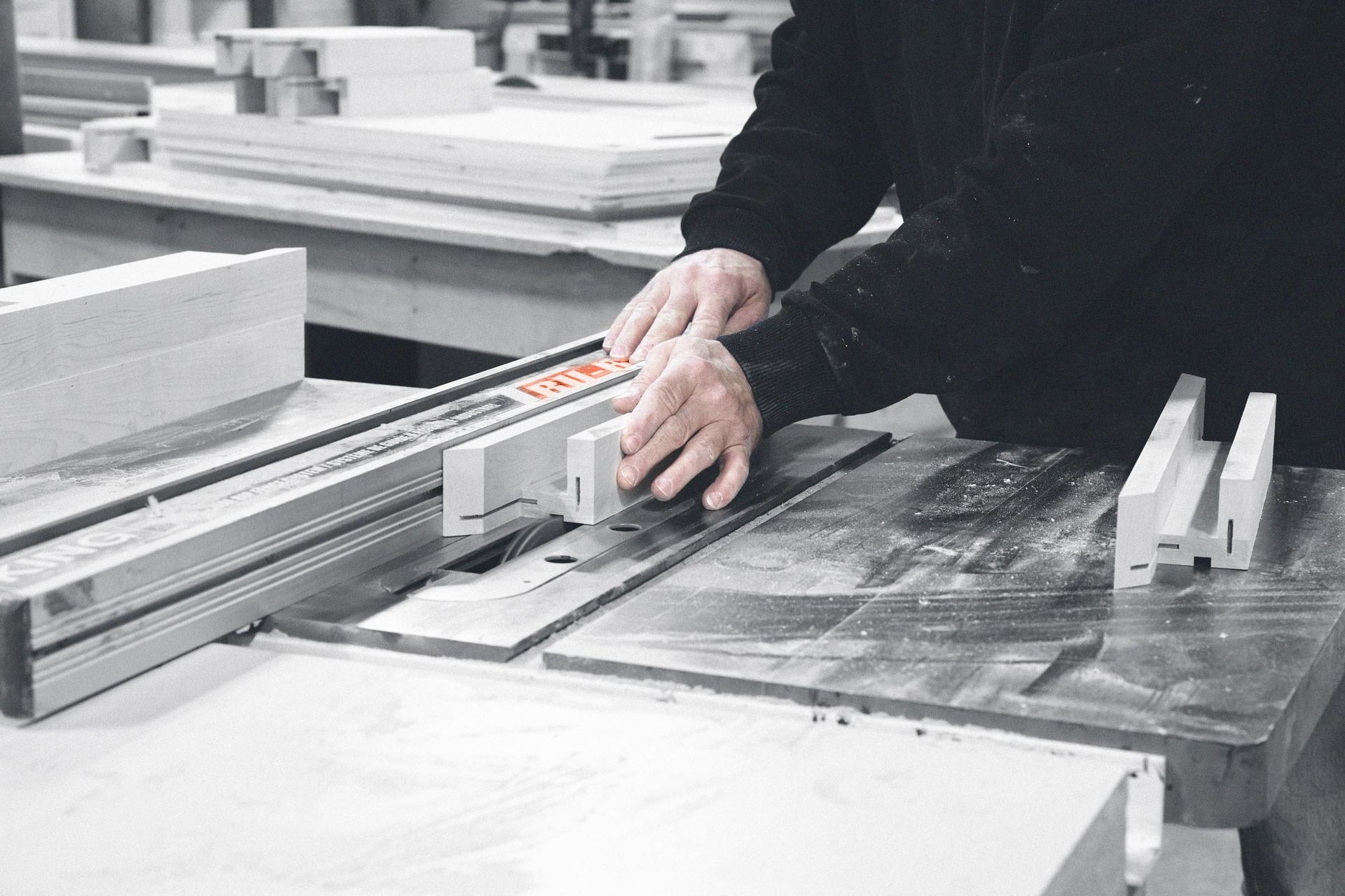A person is cutting a piece of wood on a table saw.
