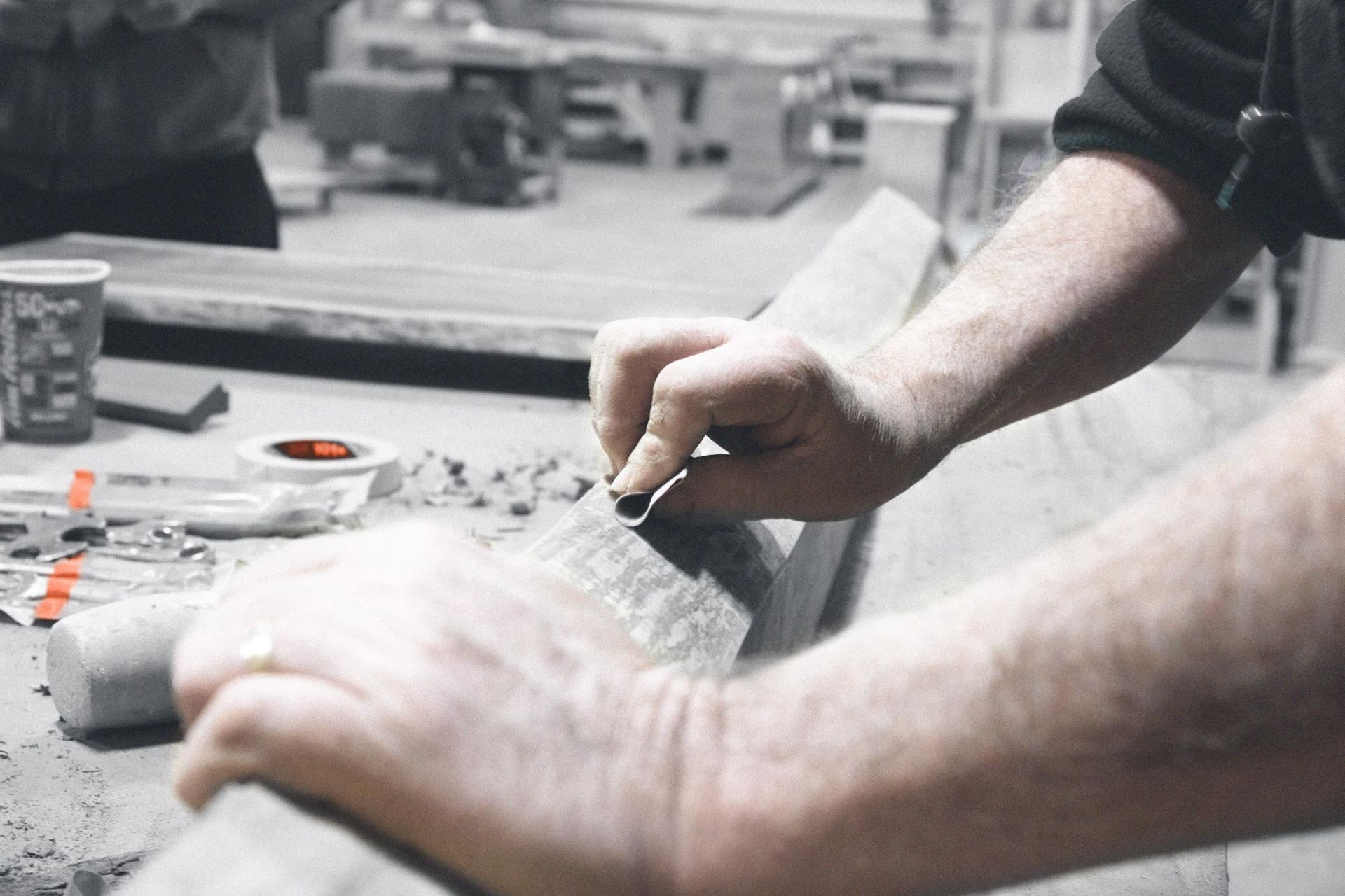 A man is working on a piece of wood with sand paper.