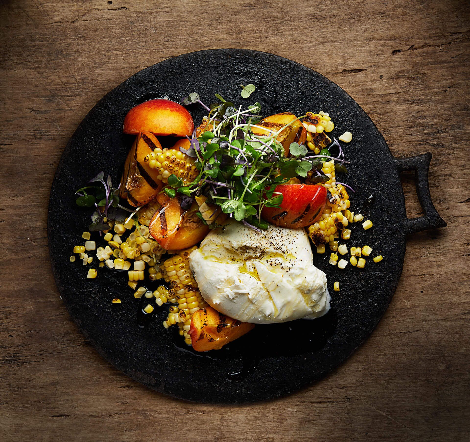 A black plate topped with vegetables and a poached egg