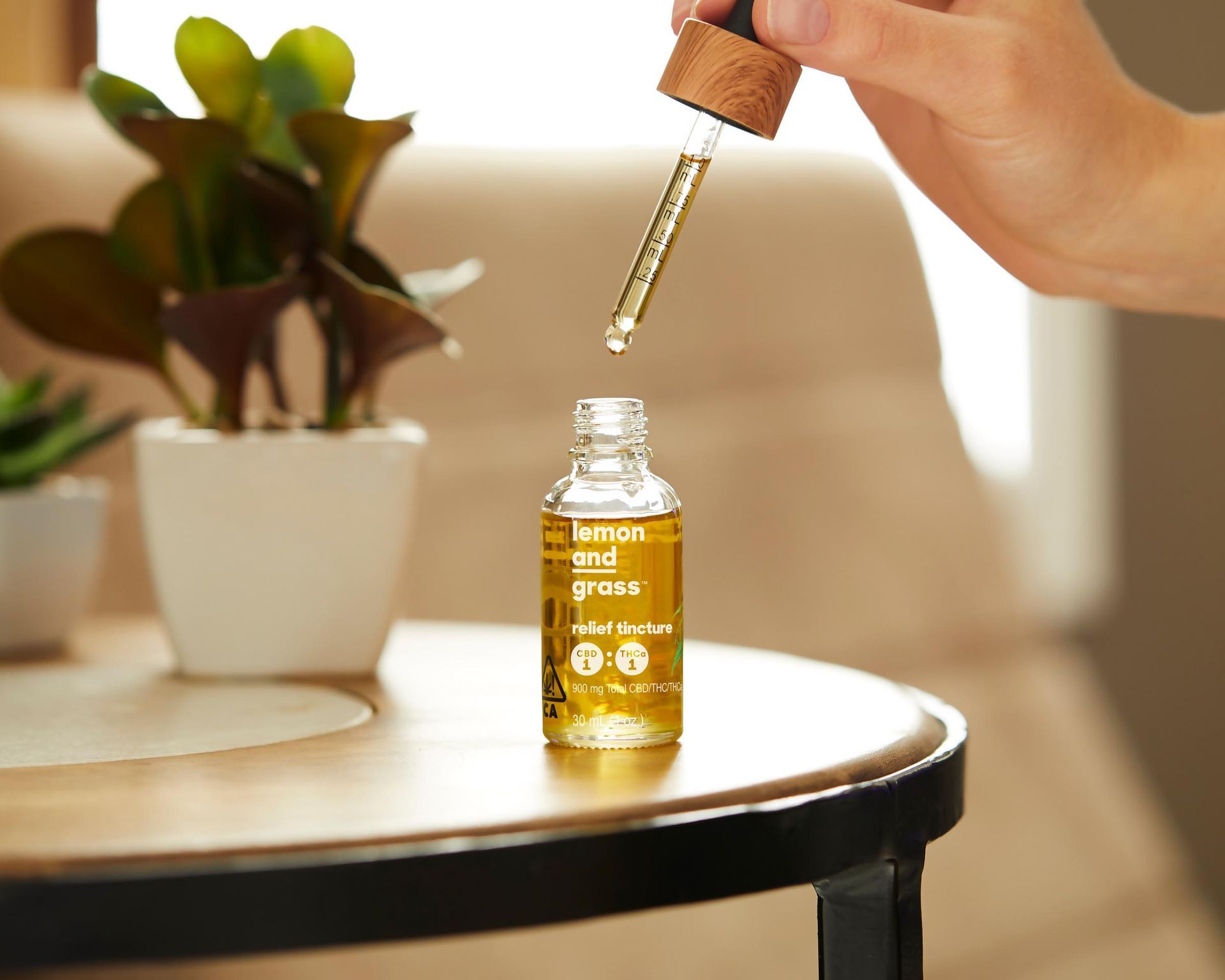 A person is holding a dropper over a bottle of tincture