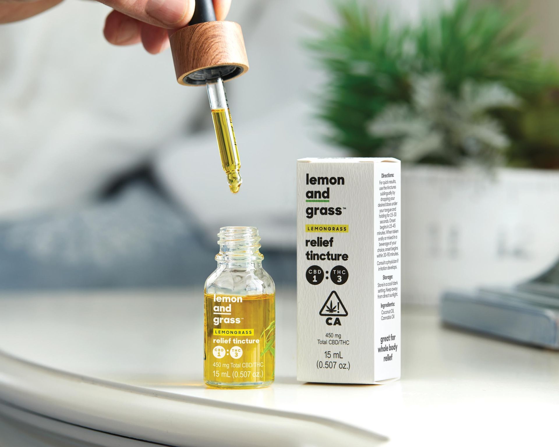 A person is holding a bottle of relief tincture next to a box.