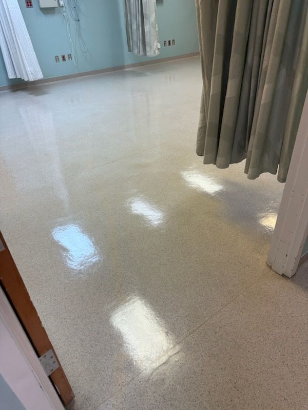 Shiny hospital hallway floor with curtains and doorway visible