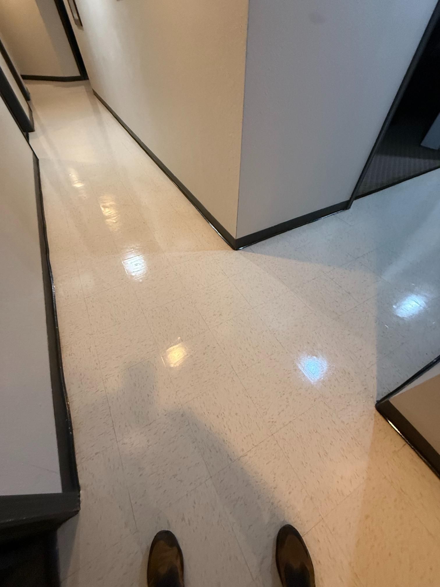 View from standing in a bright hallway with glossy white floor and doorways on both sides.