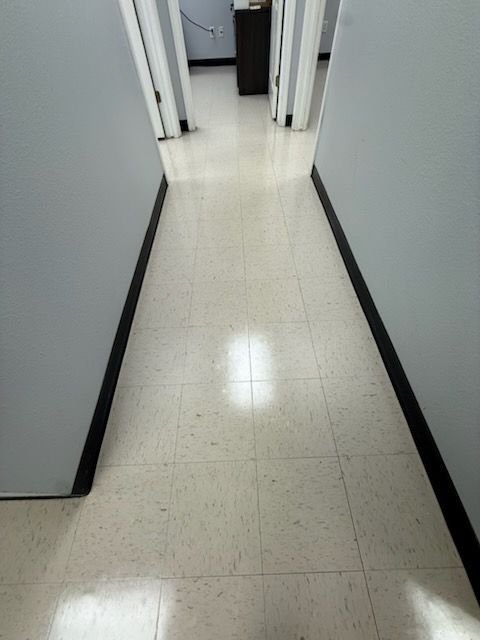 Narrow hallway with white walls and tiled floor leading to open doors ahead