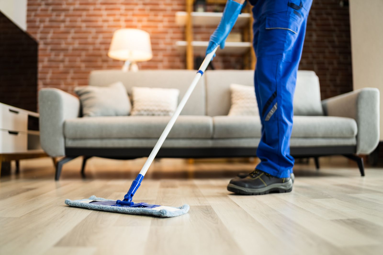 A person is mopping the floor in a living room.