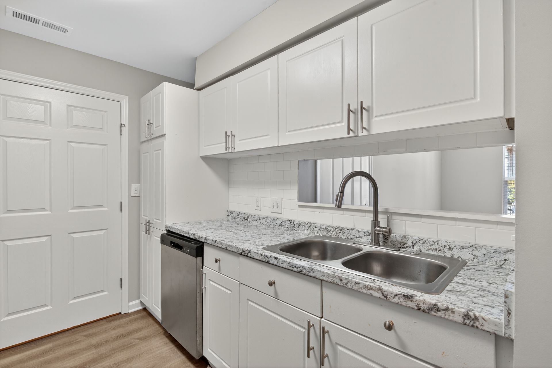 Bright white kitchen with stainless appliances, granite countertops, and double sink