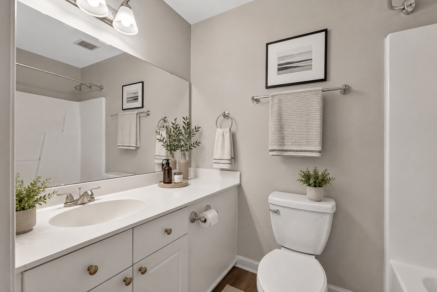 Bright white bathroom with vanity, large mirror, toilet, towel rack, and shower curtain.