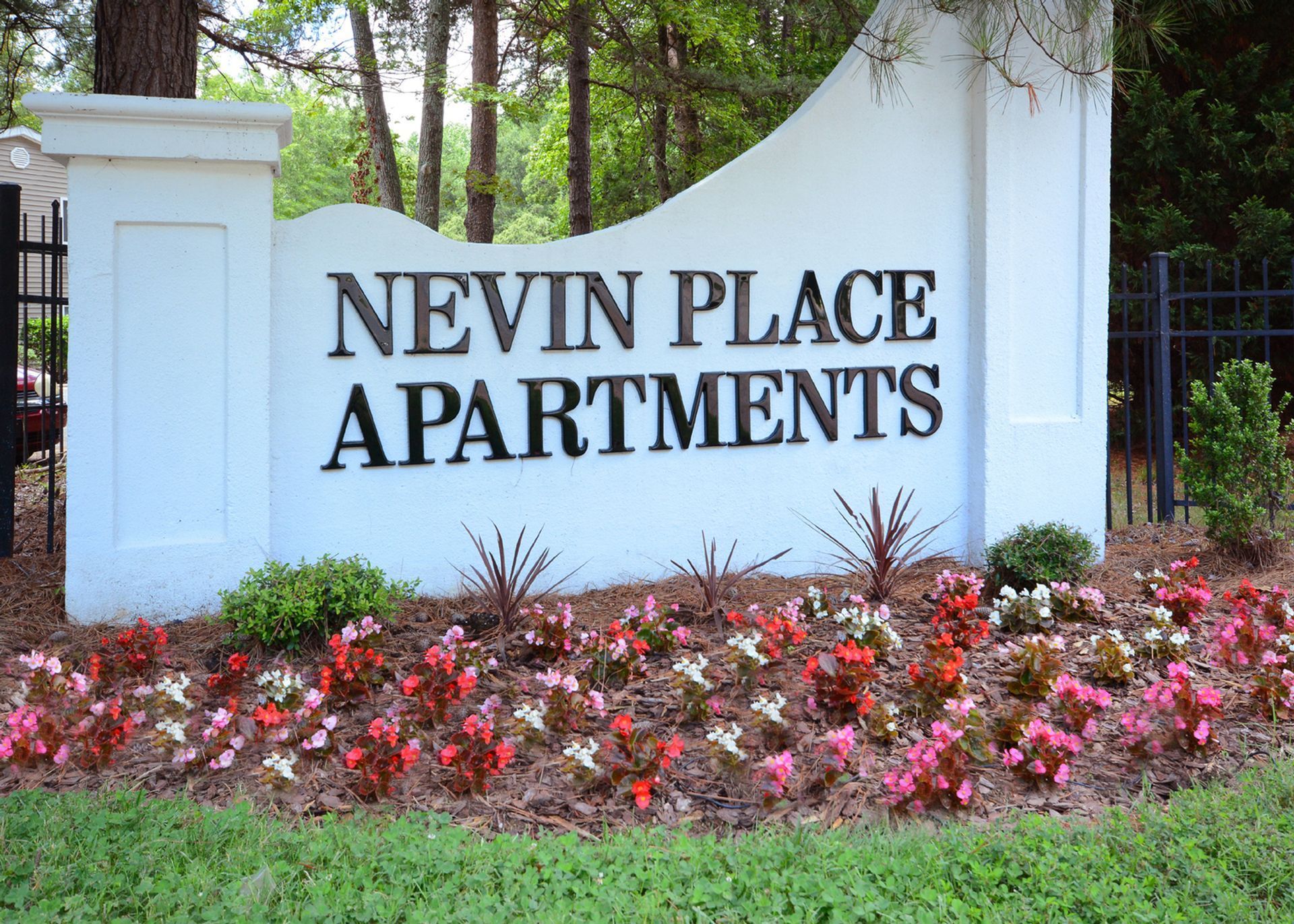 Nevin Place Apartments sign beside red flowers and greenery