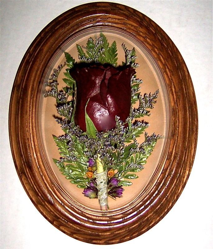 Oval-framed wall hanging with a red heart-shaped floral arrangement and greenery on a beige background