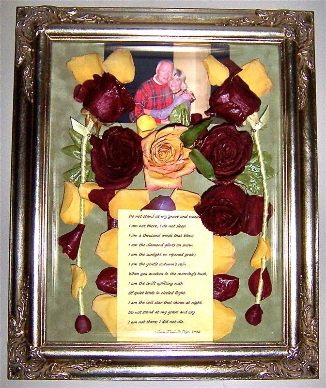 Framed pressed-flower collage with red and yellow petals around a printed poem and small central figurine
