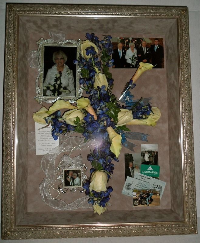 Framed memorial collage with photos, ribbons, and blue-yellow flowers on a pink background