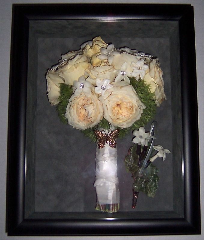 Framed bouquet of cream roses with a small white flower arrangement on a dark background