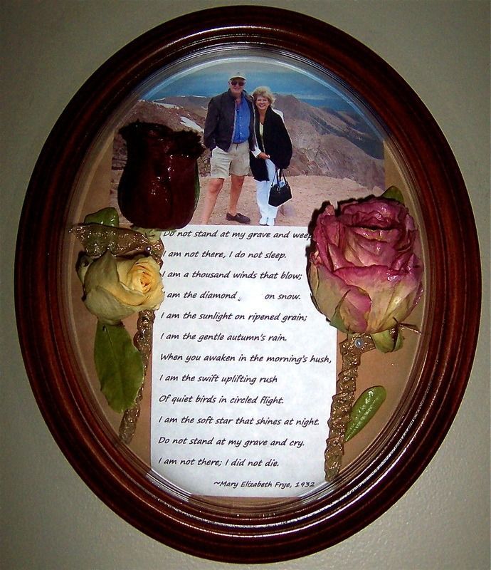 Oval framed floral memorial with two roses and a couple's photo over a poem