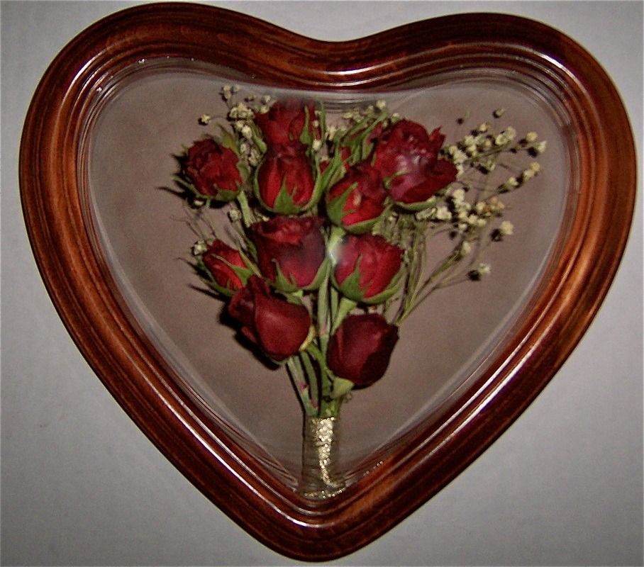 Heart-shaped wooden frame with red roses and baby's breath on a gray background