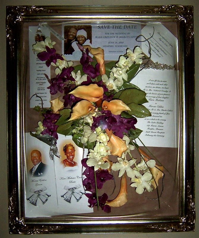 Framed memorial display with flower arrangement over a printed tribute poster and small portrait photos