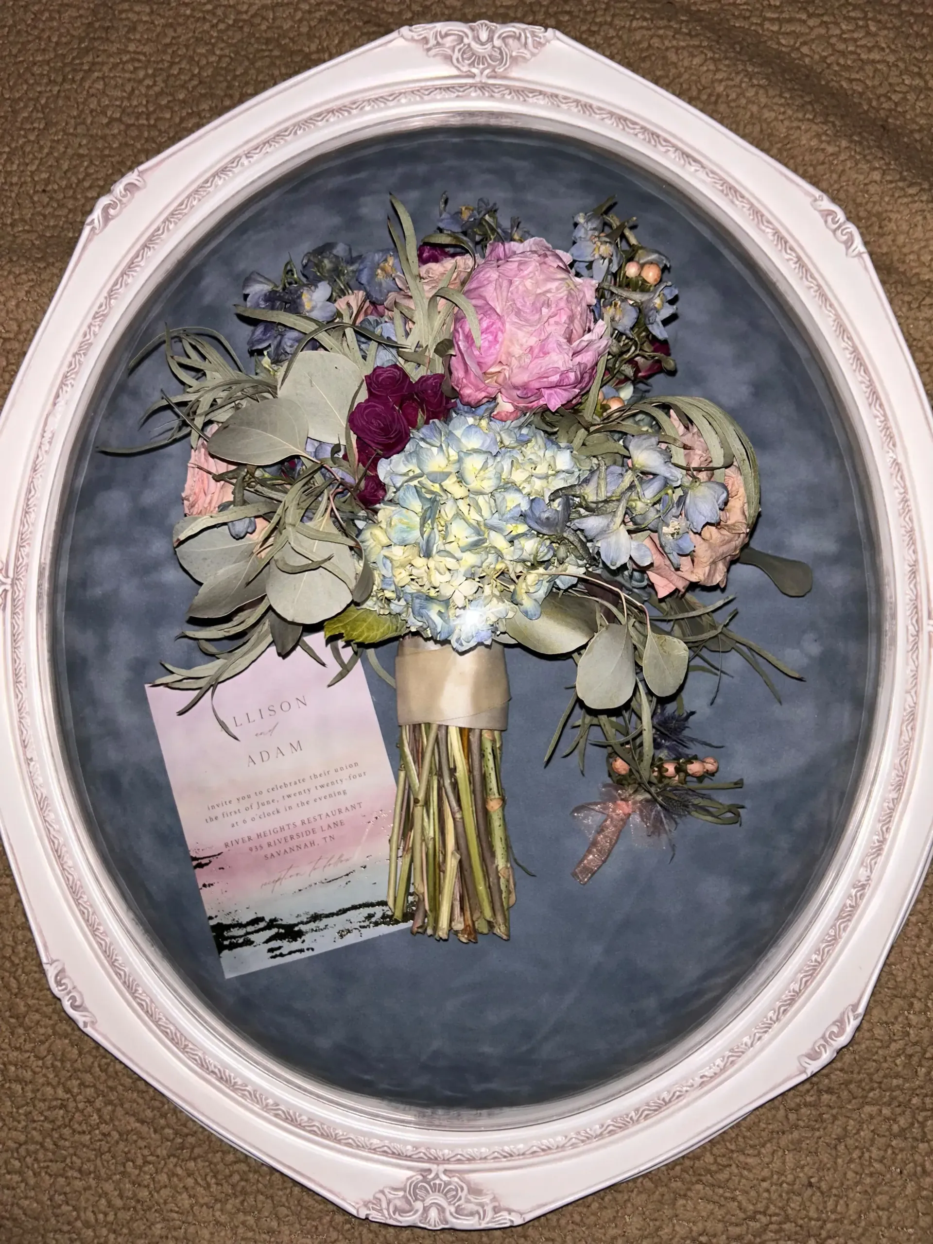 Framed dried flower bouquet with pink, white, and blue blooms on a dark background