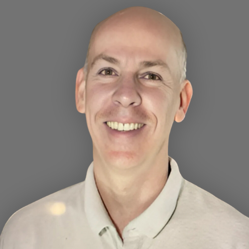 A bald man is smiling and wearing a white shirt