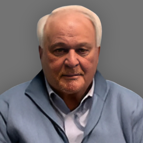 An older man wearing a blue sweater and a white shirt