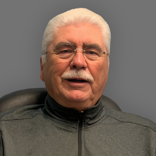 A man with glasses and a mustache is sitting in a chair.