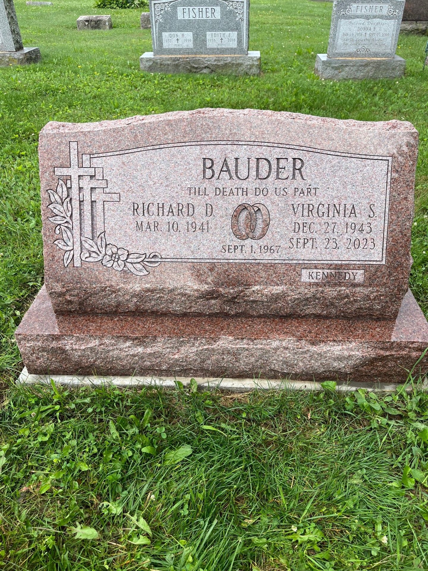 Bauder gravestone in a cemetery, pink granite marker with engraved name and dates.