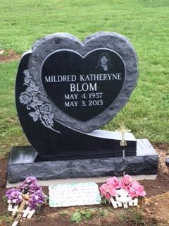 Heart-shaped gravestone for Mildred Katheryne Blom with flowers at the base in a grassy cemetery