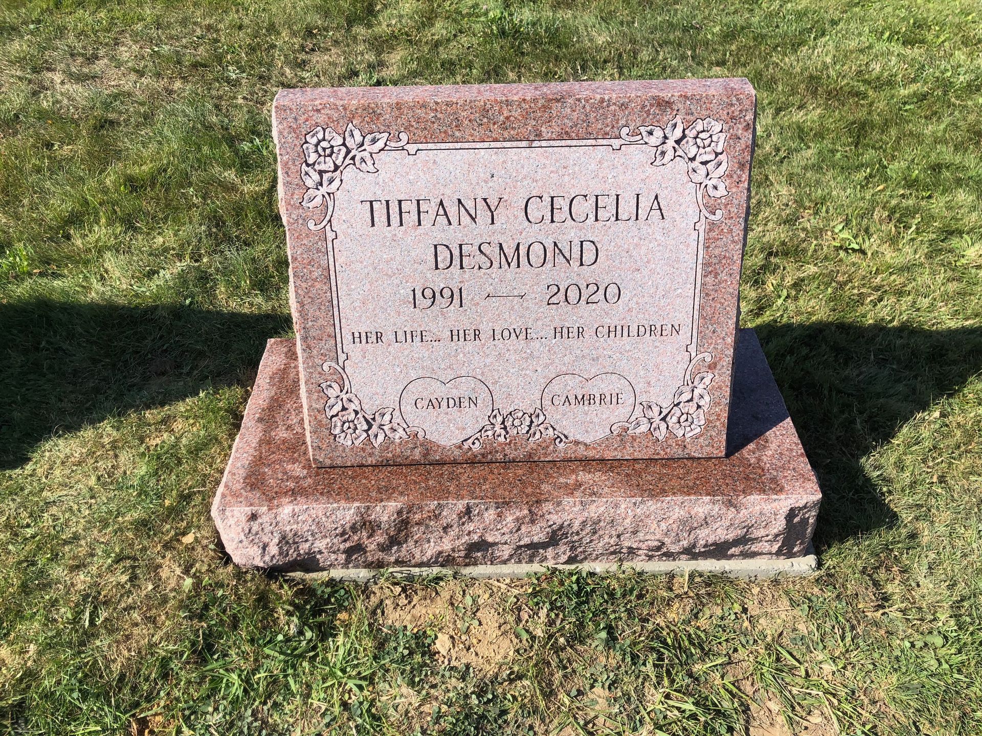 Pink granite memorial headstone in grass, engraved with the name Tiffany Cecilia Duncan and dates 1991–2020.