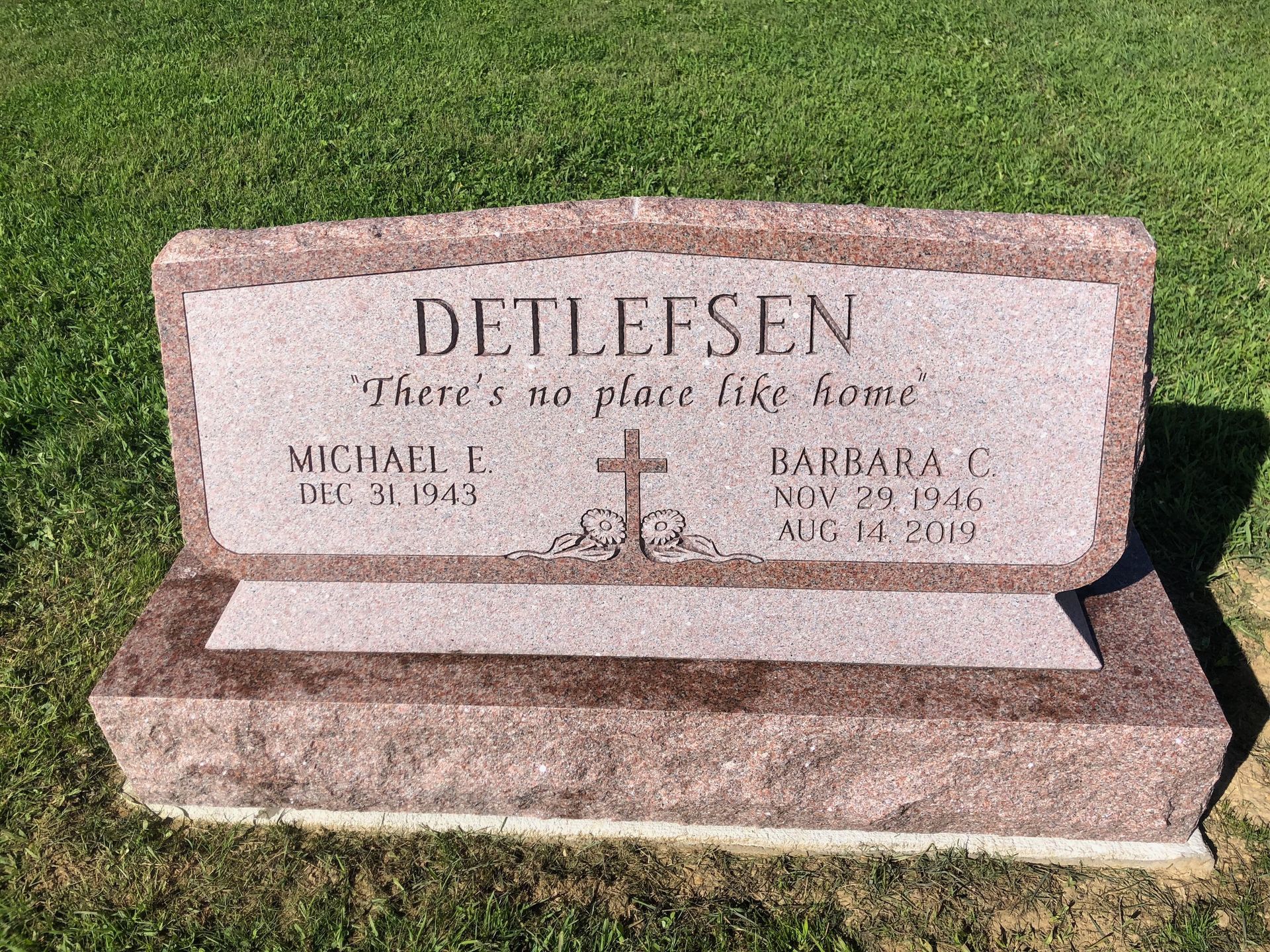 Pink granite gravestone with the name DETLEFSEN engraved on a green lawn.