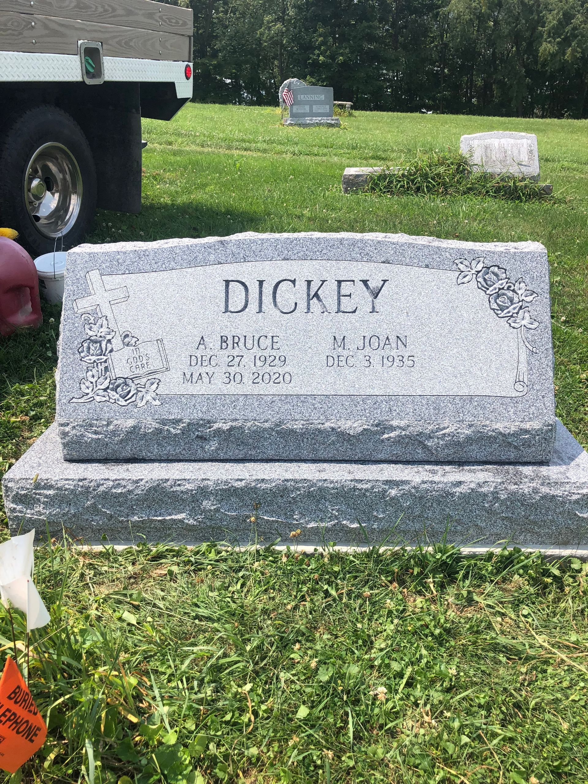 Gray granite Dickey family gravestone in a grassy cemetery, with a truck edge visible on the left.