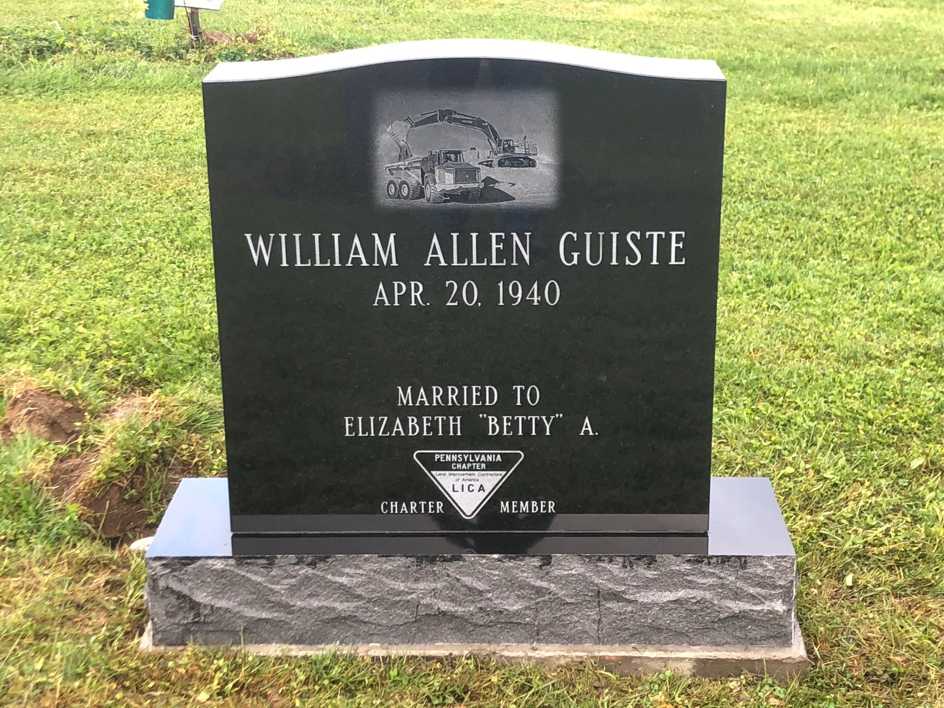 Black gravestone for William Allen Guise in a grassy cemetery, with engraved photo and memorial plaque
