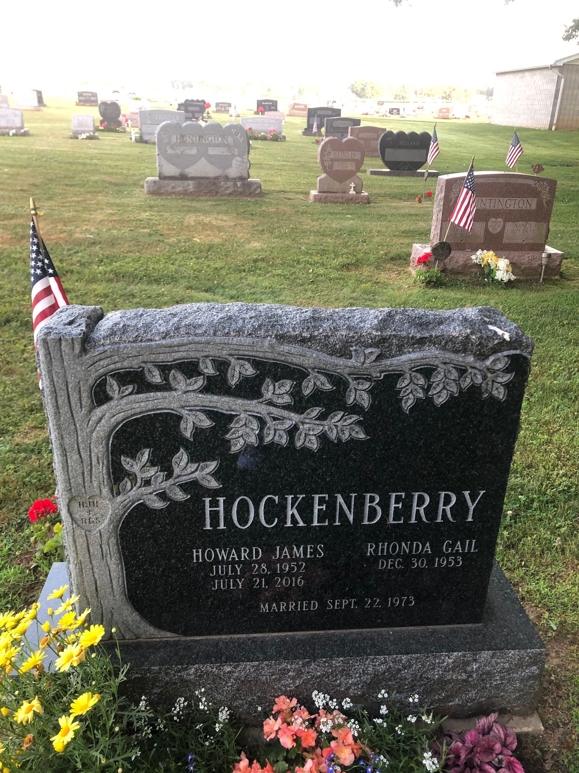 Gravestone in a cemetery with American flags and flowers, marked Hockenberry.