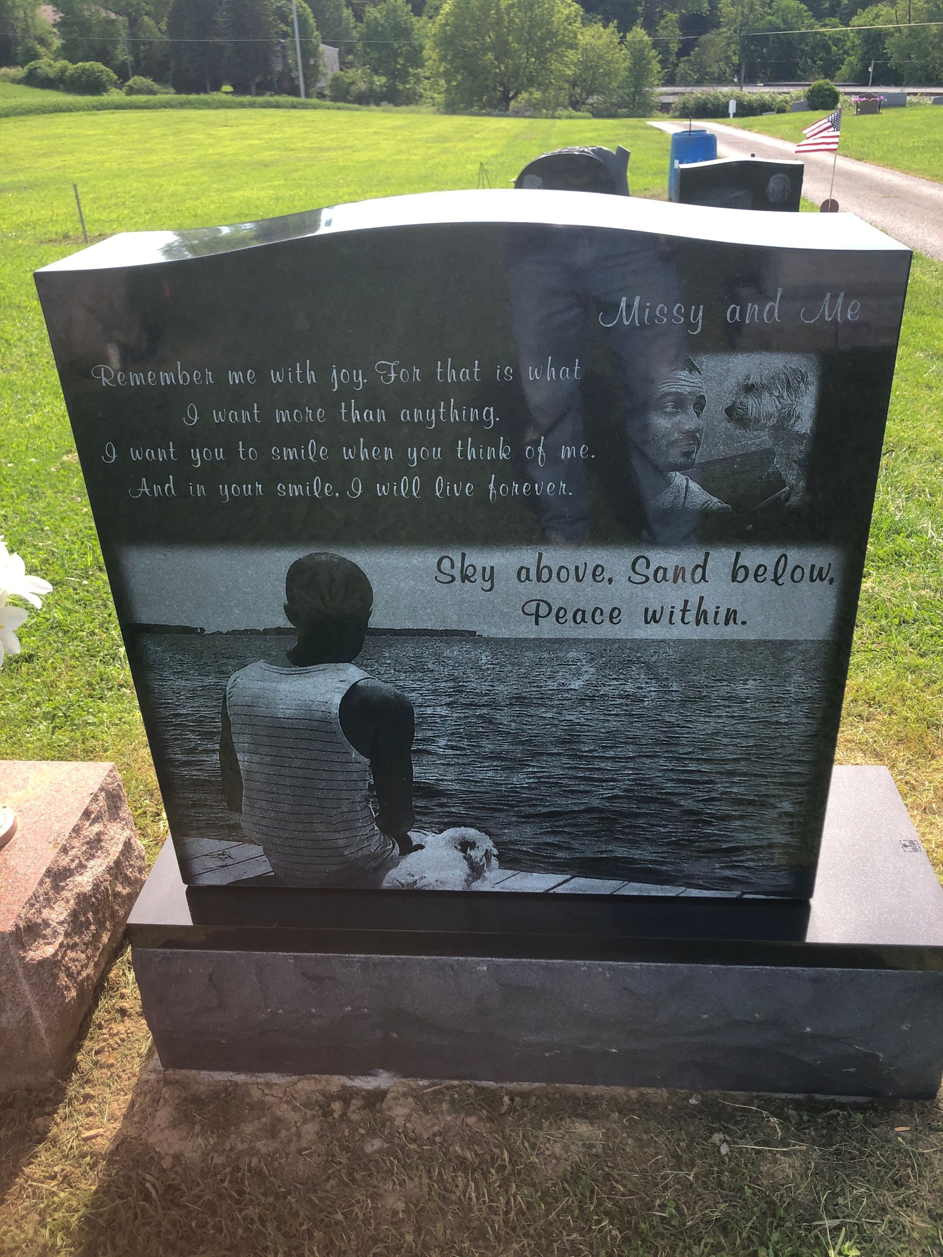 Memorial headstone with engraved photo and text in a grassy cemetery