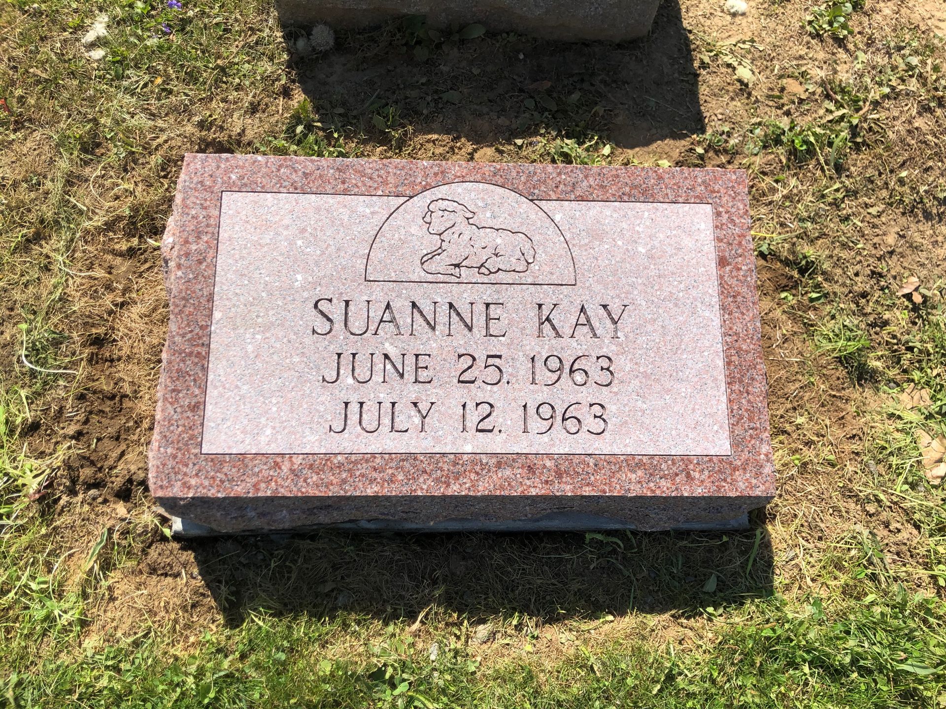 Pink granite grave marker for Suanne Kay, with birth and death dates engraved.